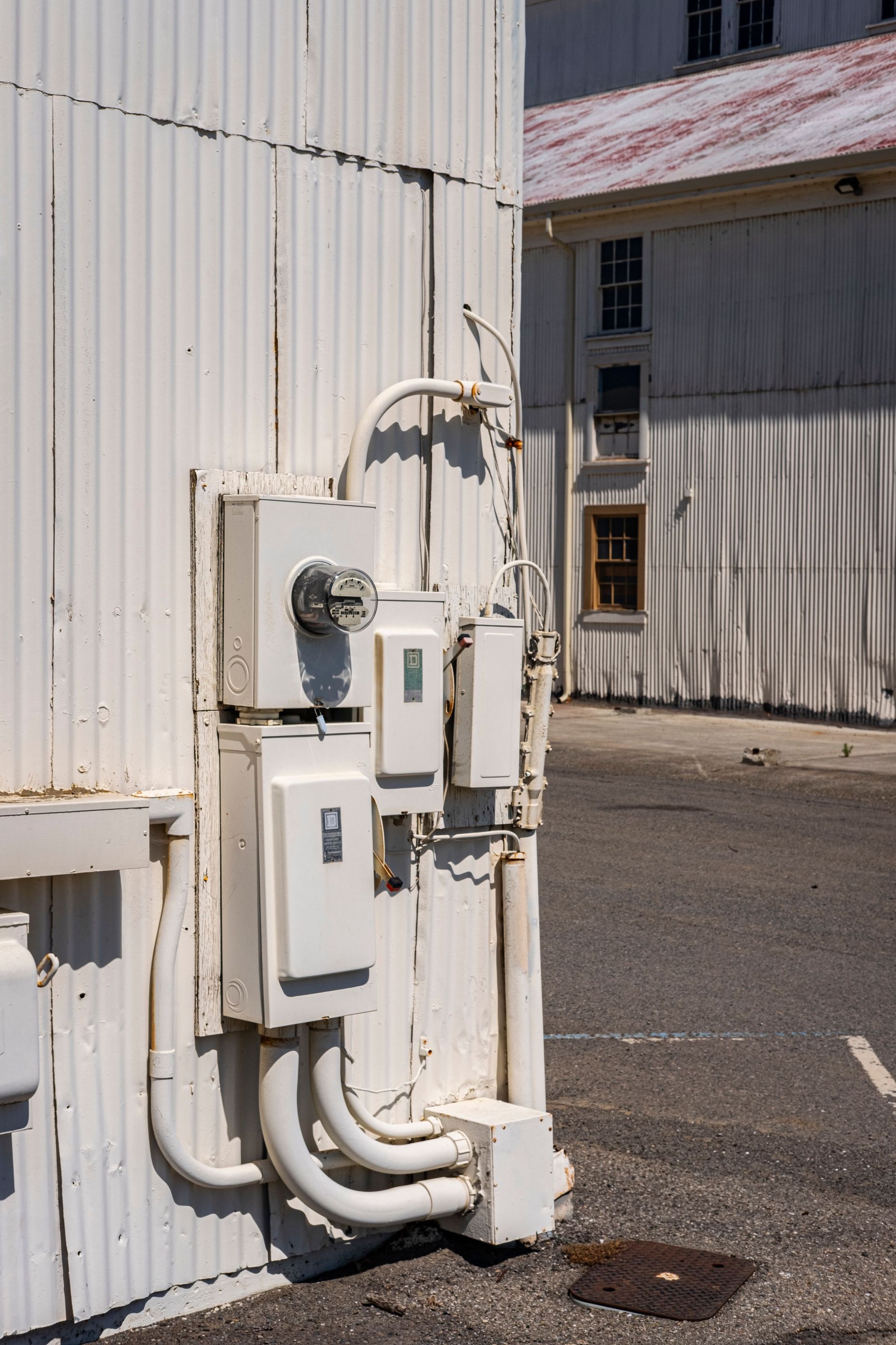 Vertical shot of electricity meters and panels mounted on an industrial building exterior.