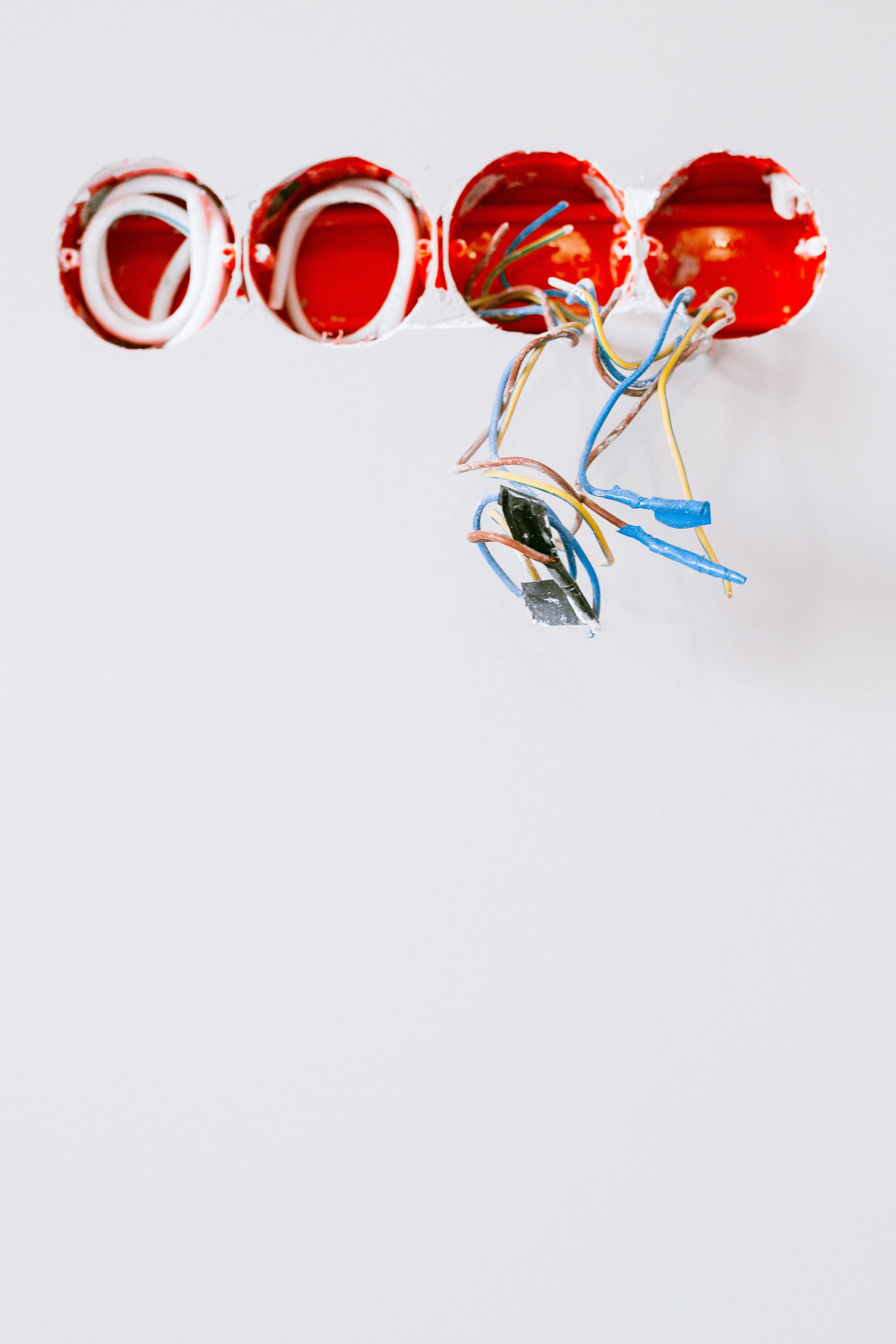 Close-up of exposed electrical wiring and sockets during renovation on a white wall.